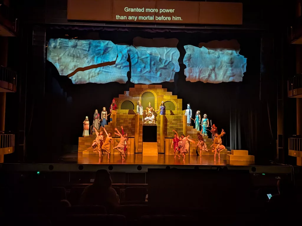 Projection seen mapped on soft goods and flying scenery. And above, the supertitles.