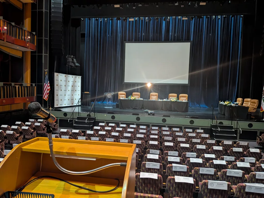 Audience view of the stage reproduction of the city council chambers with the Imag screen.
