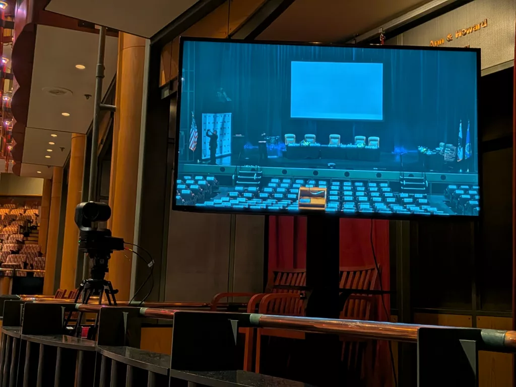 A view of one of three Panasonic PTZ cameras, and large flat screen monitors pointed at the stage for the city council members to view the broadcast of the event from.